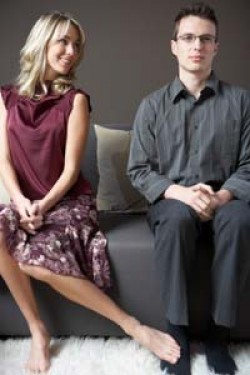 A girl touches the ankle of a quiet looking man