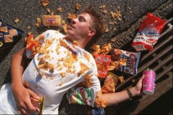 A healthy man is buried under a pile of fast food wrappers